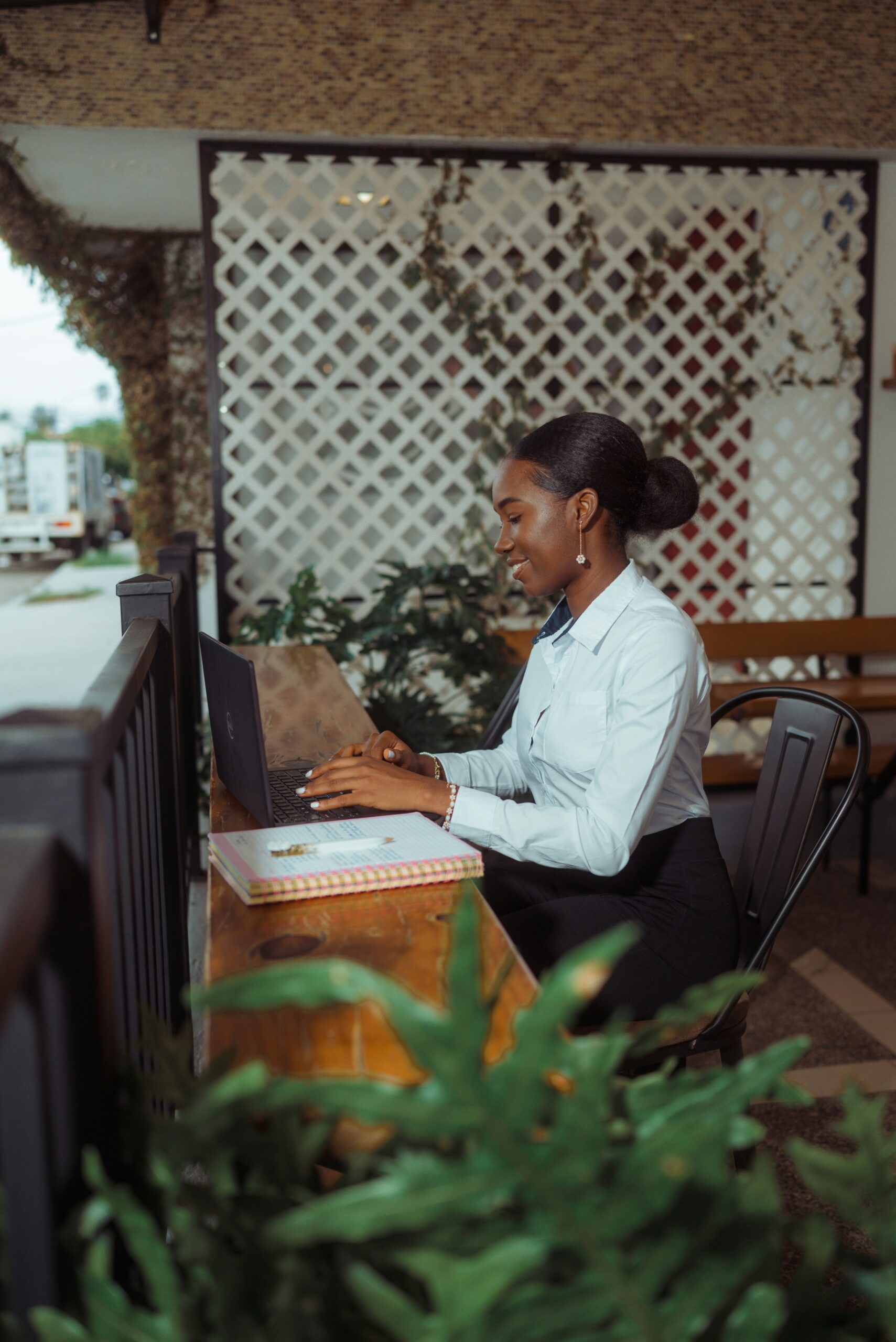 Woman working on laptop at outdoor cafe table.