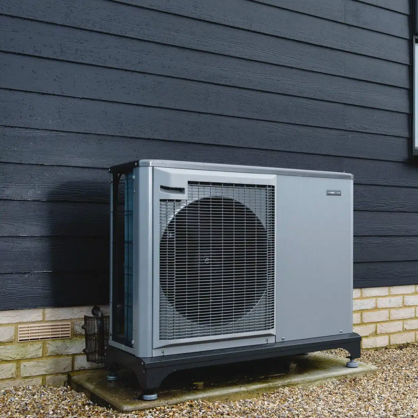 Outdoor heat pump unit on gravel base.